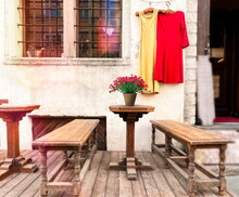 Medieval Houses And Wooden Table With  Flowers And  Bench ,vintage Dresses On Shop Windows Street Scene In Tallinn Old Town Travel To Estonia 
