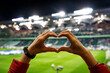 She loves this team. Heart shape for the favorite football club during a match in a stadium
