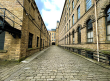 Stone Cobbled Street, Between Two Former Victorian Mills, In The Heart Of, Saltaire, Yorkshire, UK