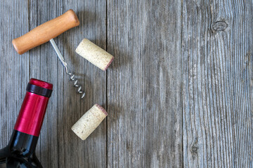 RED WINE BOTTLE, CORKSCREWS AND CORKS ON OLD WOODEN TABLE. TOP VIEW AND COPY SPACE.

