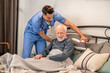 Healthcare worker helping a bedridden person sit up in bed