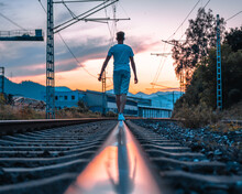 Back View Of A Young Caucasian Man Walking On The Railroad At Sunset In Slovakie