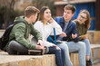 © JackF - Smiling cheerful teenagers talking with each other sitting on stairs on city street
