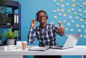 Wall Mural - cheerful smiling african american helpline center operator wearing headset, showing thumbs up approv