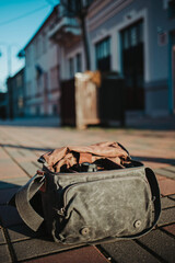 Sticker - Vertical shot of a camera in a bag on the ground with buildings in the background