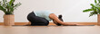 © 220 Selfmade studio - Banner Side view of Asian woman wearing green sportwear doing Yoga exercise,Yoga Child’s pose or Balasana,Calm of healthy young woman breathing meditation with yoga at home,Exercise for wellness life