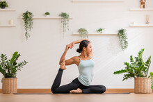 Side View Asian Woman Wearing Green Sportwear Doing Yoga Exercise.Yoga One Legged King Pigeon Pose Or Eka Pada Rajakapotasana.Calm Of Healthy Young Female Breathing And Meditation Yoga At Cozy Home