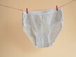 Gray panties for girls hanging on a rope attached with a clothespin, children's knitted cotton underwear