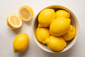 Wall Mural - Whole fresh lemons in rustic bowl next to cut lemon from above.