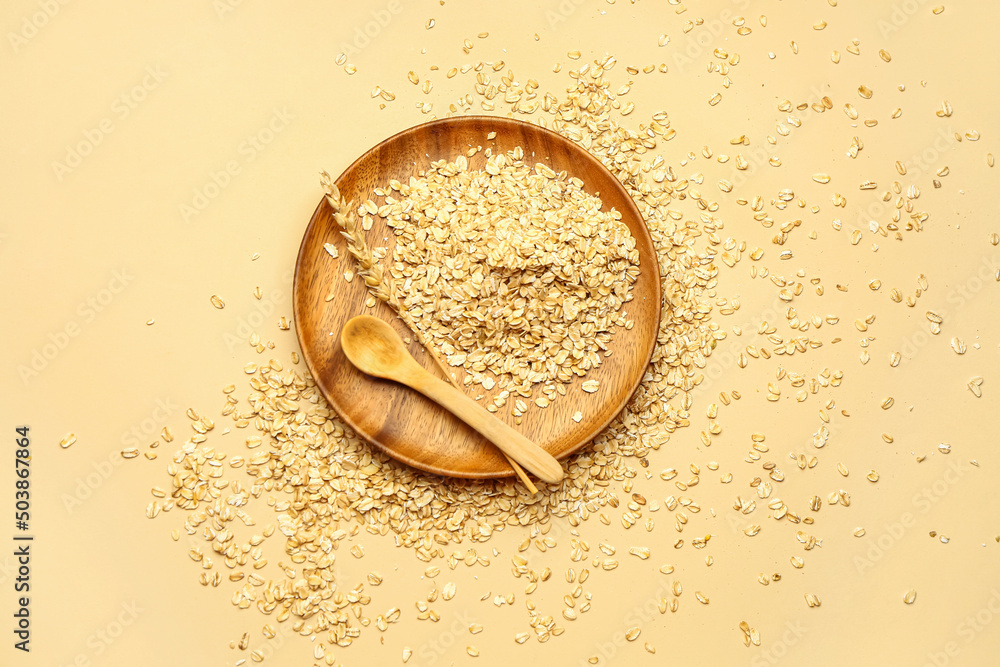 Plate of raw oatmeal and spoon on color background