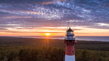 Aerial View Of The Lighthouse During Sunset. Blue Sky, Orange Sun, Pastel Pink Clouds. Sea In The Background.