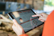 © Nattawit - Action of a working is using tablet to review factory report with blurred background of warehouse. Business management and technology concept photo. Close-up and selective focus at human's hand part.