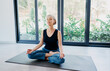 © luengo_ua - Yoga at home Senior woman in lotus pose sitting on the mat against big window. Concept of calm and meditation.