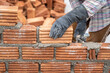 © pomphotothailand - Construction worker installing bricks masonry bricklayer and adjusting bricks walls using trowel, mortar and putty knife.