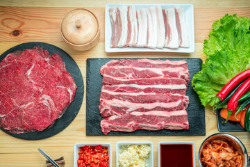 Wall Mural - Rare Sliced Wagyu beef, Cross Cut Short Ribs beef, Slide pork belly on black plate, Red beef on wooden background, Asian asian BBQ Shabu Shabu Sukiyaki food style.