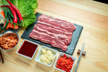 Wall Mural - Sliced Cross Cut Short Ribs beef on black plate, Beef Short Ribs (Sliced) on wooden background.