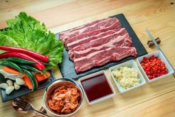 Wall Mural - Sliced Cross Cut Short Ribs beef on black plate, Beef Short Ribs (Sliced) on wooden background.