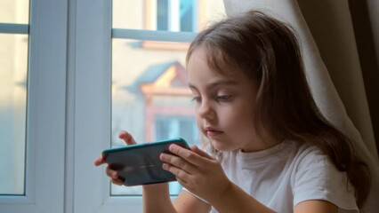 Cute preschool girl using smartphone at home.