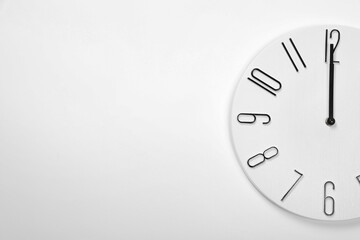 Stylish analog clock hanging on white wall, space for text