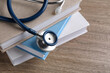 © New Africa - Student textbooks and stethoscope on wooden table, closeup view with space for text Medical education