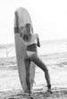 Kobieta z deską surfingową, surferka na tle oceanu na plaży.