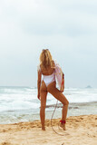 Fototapeta Fototapety z morzem do Twojej sypialni - Kobieta z deską surfingową, surferka na tle oceanu na plaży.