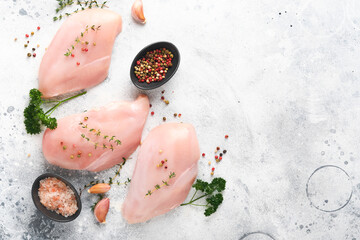 Wall Mural - Chicken breast. Raw chicken breast fillets on black ceramic plate on wooden cutting board with herbs and spices on old grey table background. Top view with copy space.