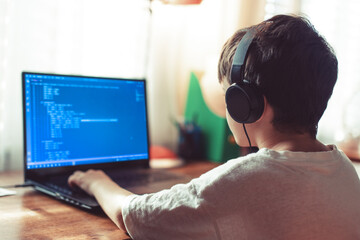 young geek boy coding on laptop at home