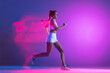 © master1305 - Professional female athlete, runner training isolated on blue studio background in mixed pink neon light. Healthy lifestyle, sport, motion and action concept.