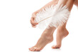 Female feet with smooth skin and soft ostrich feather on white background