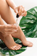 Wet female feet and bottle of nourishing cuticle oil with dropper