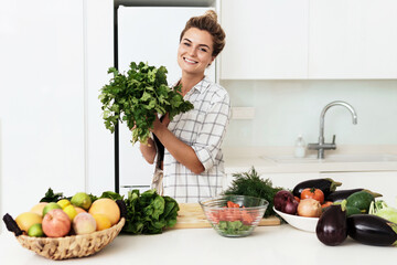 Wall Mural - Woman with big bunch of green coriander during cooking in the kitchen