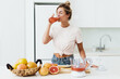 Leinwandbild Motiv Woman drinking freshly squeezed homemade grapefruit juice in white kitchen