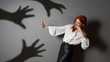 terrified woman in defensive posture is attacked by shadows of hands