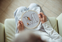 Overhead View Of A Woman Holding An Embroidery Hoop With The Letter M