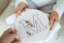 Woman Giving An Embroidery Hoop With The Letter M To Her Senior Mother