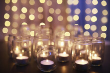 Background With Candles In Glass Vessels. Candles Burn In A Dark Place. Rest In Peace.
