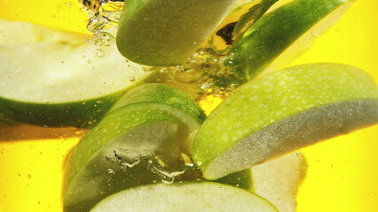 Wall Mural - Close up of green apple slices in water.