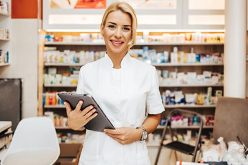 Young and attractive female pharmacist working in a drugstore. She is happy and smiled.