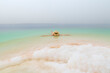 Girl with hat is relaxing and swimming in the Dead Sea