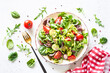 Green salad on white background. Fresh salad leaves and vegetables in white plate. Healthy vegan food, diet food. Top view image.