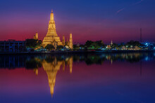 View Of The Wat Arun Temple At Sunset With Reflections In The Water
