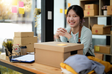 Wall Mural - Startup small business entrepreneur SME, asian woman packing box. Portrait of young Asian small business owner in home office, online sell marketing delivery, SME e-commerce telemarketing concept