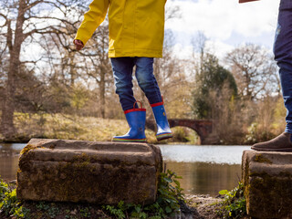 Wall Mural - Father with son on stepping stones on lake, low section