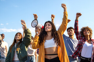 Young female activist leader giving speech and cheering protesters in demonstration for human rights.