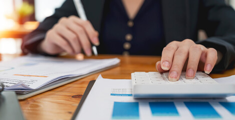 Wall Mural - Close up Business woman hand using calculator to calculate the company's financial results and budget.