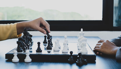 Wall Mural - The hands of businesswomen two people moving chess in chess competitions demonstrate leadership, followers, and strategic plans, business success building processes, and teamwork