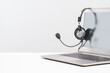 Side view of slim laptop with headset on white desk. Monochrome background. Distant learning. working from home, online courses or support. Audio podcast headphones . Helpdesk or call center banner
