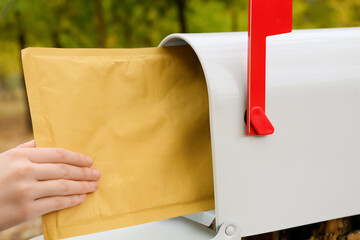 Wall Mural - Woman getting letter from mailbox in park, closeup