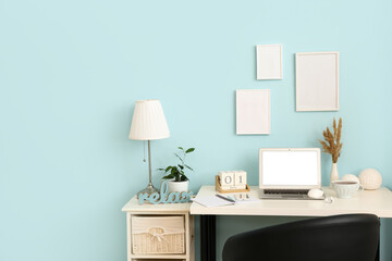 Wall Mural - Comfortable workplace with modern laptop, mobile phone, earphones and cup of tea near color wall